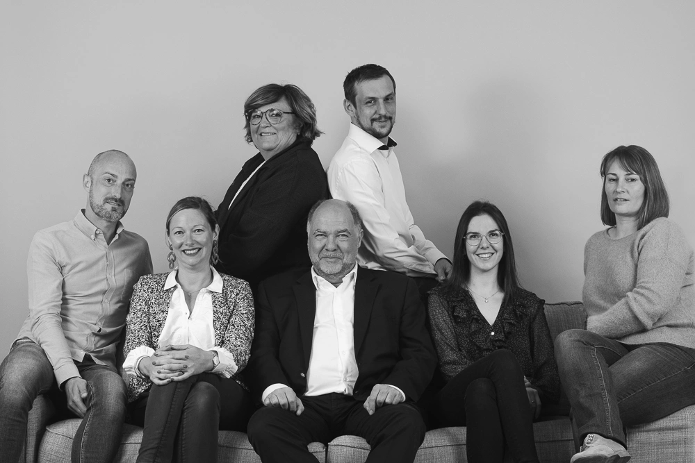 Portrait en noir et blanc de sept collègues réunis autour d'un canapé.