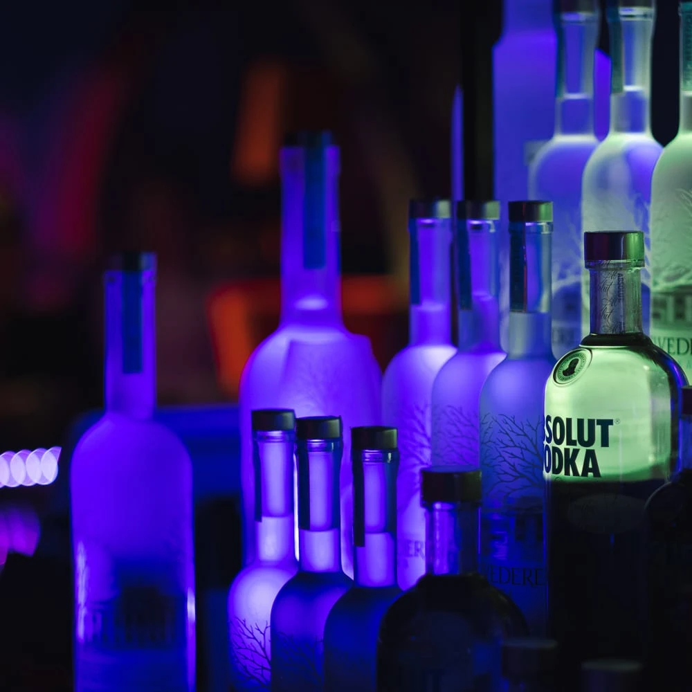 Bouteilles éclairées en bleu et violet dans une présentation de produits.