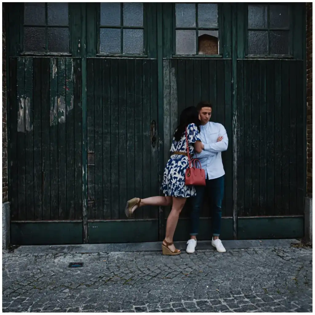 Couple complice devant une porte ancienne vert sombre lors d'une séance photo d'engagement.