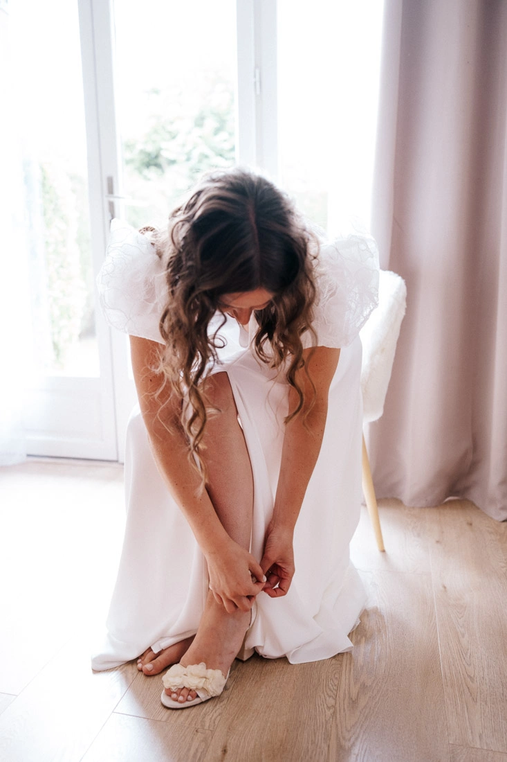 Mariée ajustant la bride de sa chaussure fleurie pendant ses préparatifs.