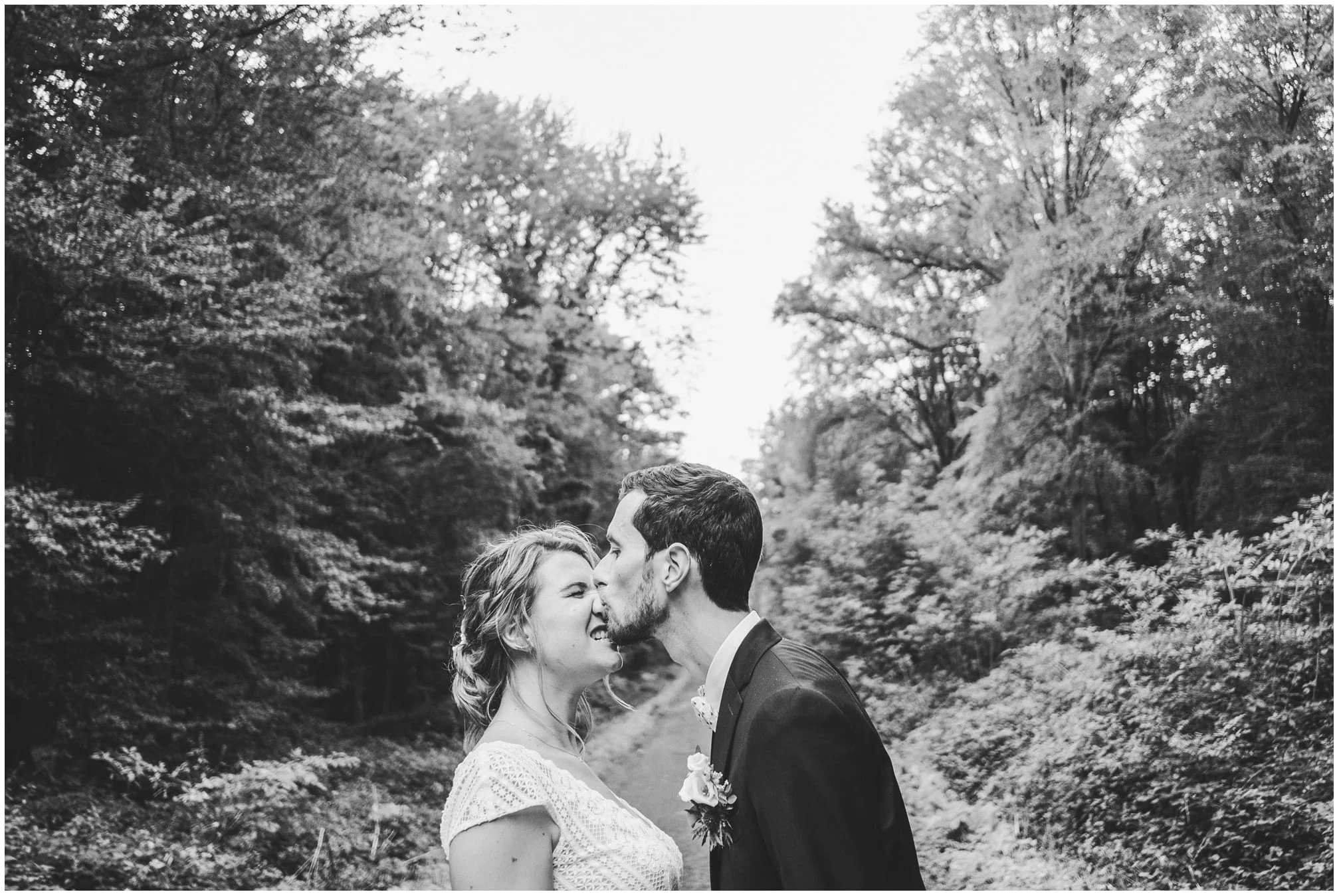 Couple s'embrassant sur un sentier d'altitude devant des sommets enneigés.