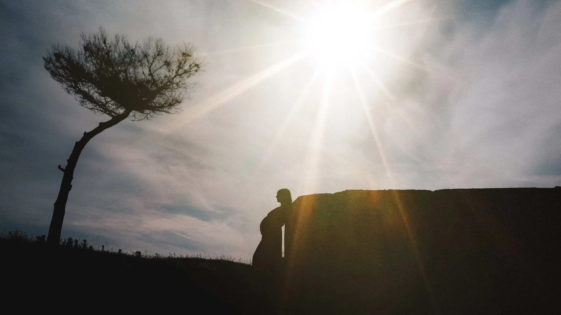 Silhouette d'une femme enceinte de profil devant un coucher de soleil.