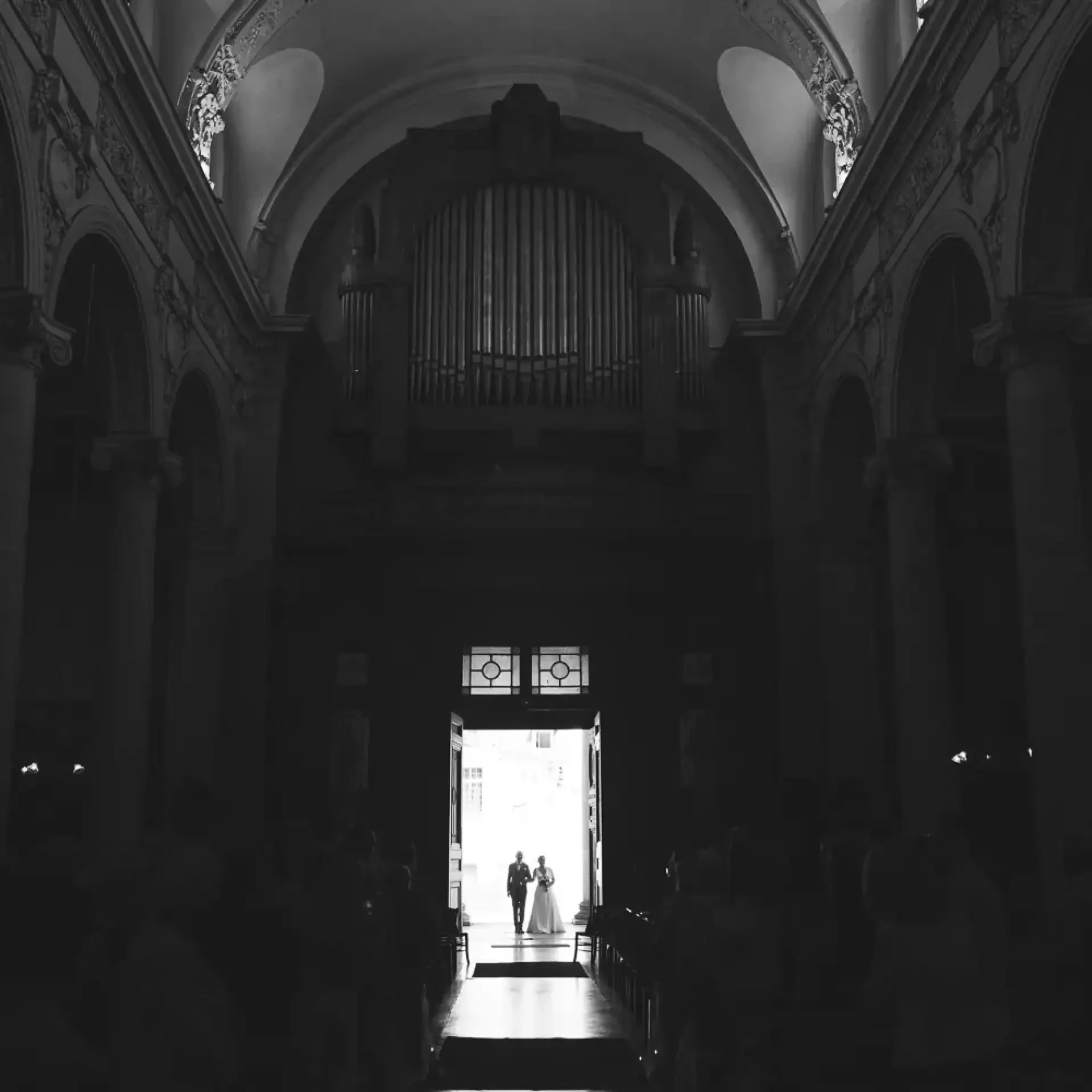 Silhouette de Célia et Louis dans l'entrée lumineuse de l'église.
