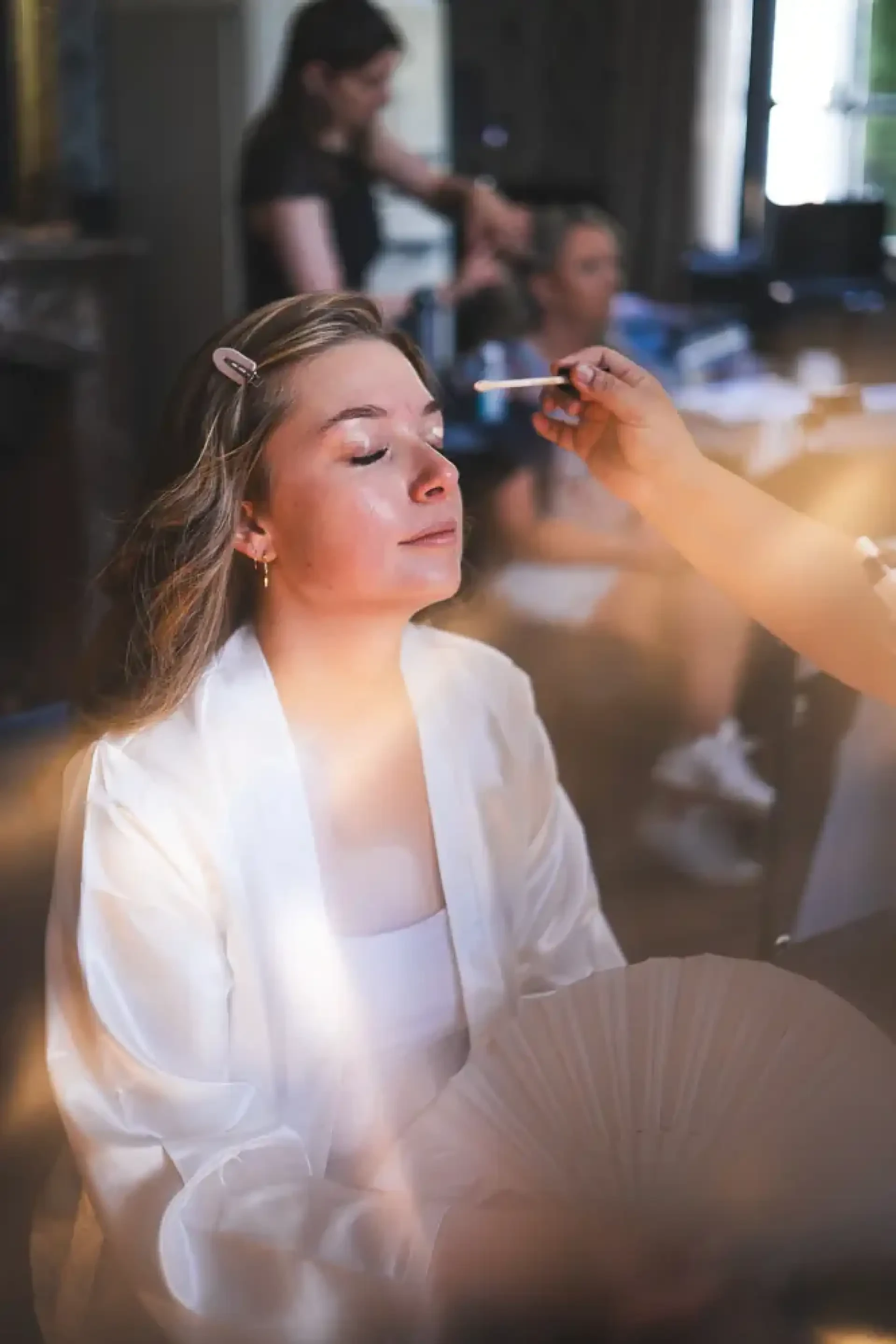 Célia les yeux fermés pendant son maquillage dans la lumière du matin.