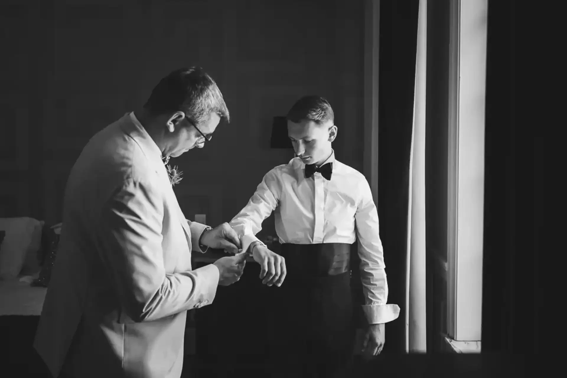 Père et fils préparant le costume de Louis dans une photographie en noir et blanc.