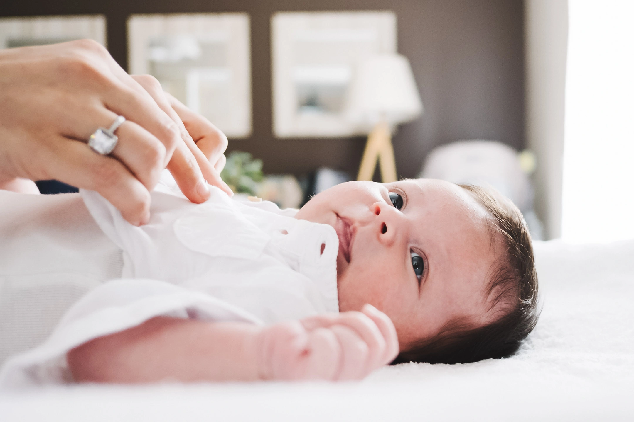 Nouveau-né allongé sur un lit blanc pendant une séance photo de naissance dans une chambre lumineuse.
